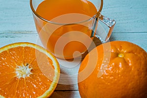 A glass of fresh orange juice with sliced oranges on a wooden table. Preparation of fresh orange juice