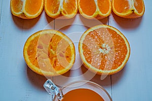 A glass of fresh orange juice with sliced oranges on a wooden table. Preparation of fresh orange juice