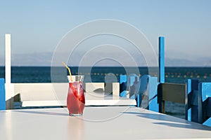 glass of fresh red juice on table near the sea. cherry drink standing in greece restauraunt. Korfu