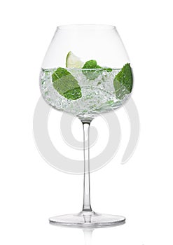 Glass of fresh sparkling water lemonade with mint and ice cubes and lime slice on white background