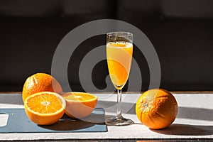 Glass of fresh squeezed orange juice with raw oranges on cutting board isolated on black background. Healthy eating.