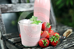 Glass of fresh strawberry shake, smoothie or milkshake and fresh strawberries on table. Healthy food and drink concept