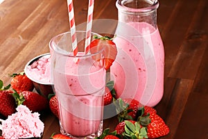 Glass of fresh strawberry shake, smoothie or milkshake and fresh strawberries on table. Healthy food and drink concept