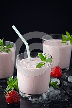 Glass of fresh strawberry shake, smoothie or milkshake and fresh strawberries on table. Healthy food and drink concept with juicy