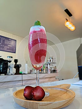 Glass of fresh strawberry smoothie and fresh strawberries on wooden plate. Healthy food and drink concept