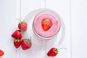 A glass of fresh strawberry smoothie on a white wooden background. Summer drink shake, Vegetarian diete and refreshment photo