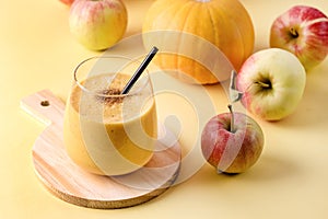 Glass of Fresh Tasty Pumpkin and Apples Juce or Smoothie with Cinnamon with Black Strew on Wooden Cutting Board Ripe Apples and