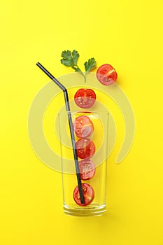 Glass, fresh tomatoes, parsley and straw on background, flat lay