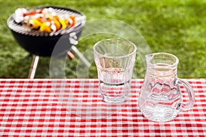 Glass of fresh water with a jug on a picnic table