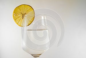 Glass of fresh water with lemon on wooden table close up