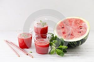 Glass of fresh watermelon smoothie covered with mint leaves