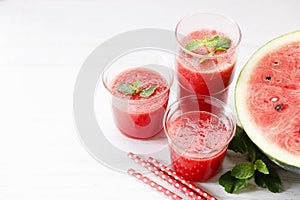 Glass of fresh watermelon smoothie covered with mint leaves