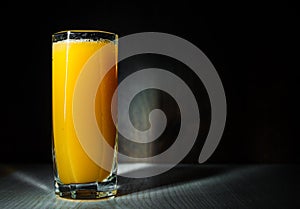 Taza fresco presionado naranja jugo sobre el oscuro negro 