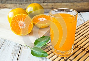 Glass of freshly pressed orange juice with sliced orange on wood