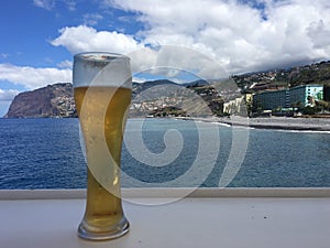 A glass of frosty ice cold beer against the ocean background