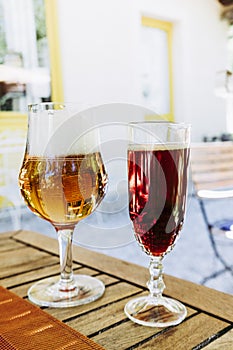 Glass of frothy craft lager beer and glass of chestnut kir - Fresh aperitif