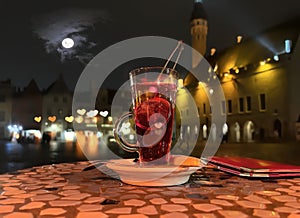 Glass of fruite teaa pn table top at street restaurant in medieval evening city Tallinn old town