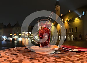 Glass of fruite teaa pn table top at street restaurant in medieval evening city Tallinn old town