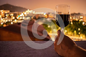 Glass full of red wine held by a young male hand photo