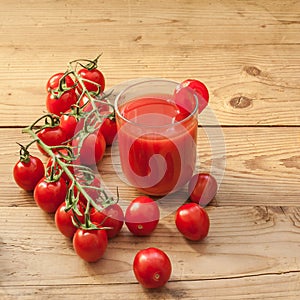 A glass full of tomato juice surrounded by freshly picked tomatoes