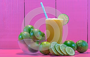 Glass of Galician lemon juice Citrus auranti and halved fruits on pink background