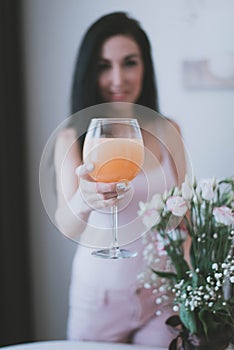 glass glass with orange juice in the hands of a brunette girl close-up