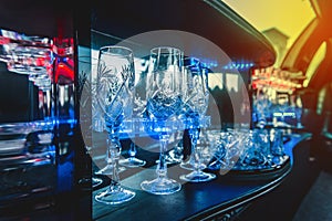 Glass glasses in neon lighting inside the luxury car limousine