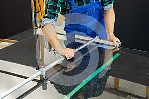 Glass glazier, cuts glass panes with specialized tools, Glass factory, close up