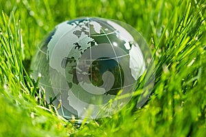 Glass globe ball in light rays on grass background