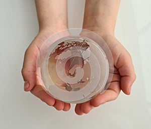 Glass globe in children hands closeup, World ecology concept