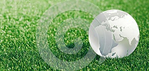 Glass globe or earth in green grass showing eco concept with copyspace, 3d rendering