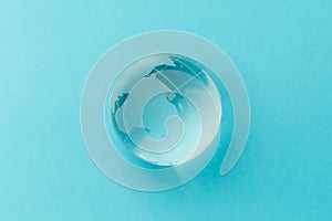 Glass globe on a light blue background. Nature concept for environment and conservation