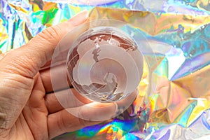 Glass globe of the planet in hand holds a girl on a colored background