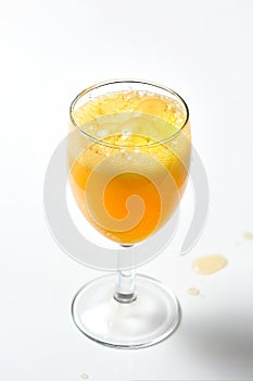 Glass goblet with bubbling orange liquid on a white background.