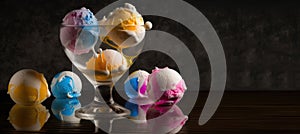 Glass goblet with multi-colored ice cream balls on a black background with balls on the table. AI generated