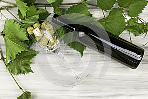 Glass goblet with wine stoppers wine bottle and grape branches on a painted wooden background