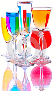 Glass goblets with colored drinks stand on a glass surface