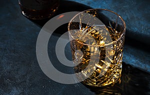 Glass of golden scotch whiskey on dark bar table background, selective focus