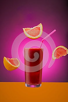 Glass of grapefruit juice isolated on a pink background. photo