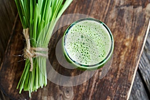 A glass of green barley grass juice with fresh barley grass