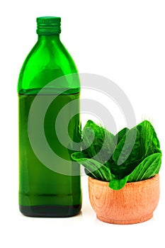 Glass green bottle and herbs in wooden bowl isolated on white background