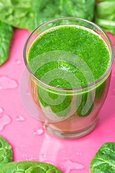 Glass with Green Fresh Smoothie from Leafy Greens Vegetables Fruits. Apples Bananas Kiwi Zucchini Spinach Leaves Pink Background