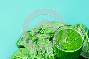 Glass with Green Fresh Smoothie from Leafy Greens Vegetables Fruits. Apples Bananas Kiwi Zucchini Scattered Spinach Leaves