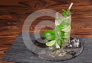 A glass of green mojito. Sour, cold and alcoholic mojito with lime and mint. Alcohol drink on a wooden background. Copy space.
