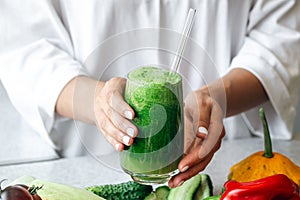 A glass of green smoothie in female hands, detox, diet and healthy eating.
