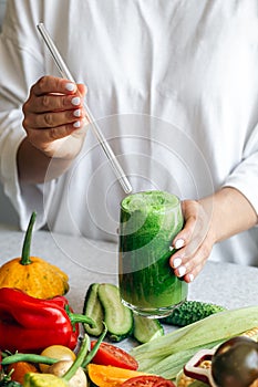 A glass of green smoothie in female hands, detox, diet and healthy eating.