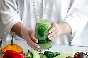 A glass of green smoothie in female hands, detox, diet and healthy eating.