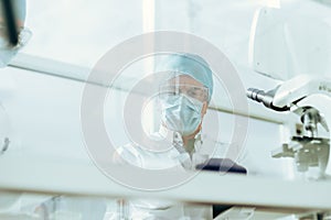 through the glass. group of scientists in protective masks work in the laboratory.