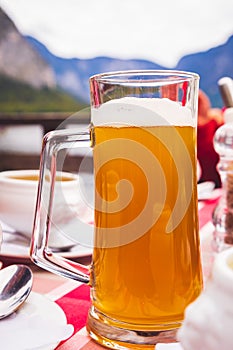 A glass of Hallstatt local beer on the table at a romantic restaurant beside the Hallstattersee Lake in High Alps Mountains, a