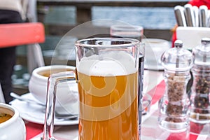 A glass of Hallstatt local beer on the table at a romantic restaurant beside the Hallstattersee Lake in High Alps Mountains, a